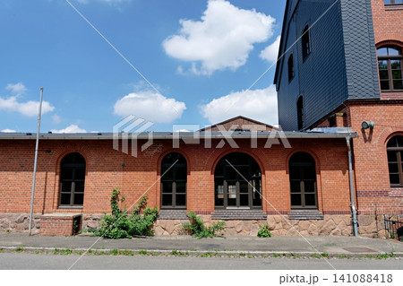 Arched windows on old red brick building with stone foundation 141088418