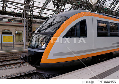 Modern passenger train waiting at covered railway station platform with arched roof Modern passenger train waiting at covered railway station platform with arched roof 141088453
