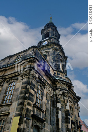 Low angle view of historic dark stone church tower with clock under cloudy sky Low angle view of historic dark stone church tower with clock under cloudy sky 141088455