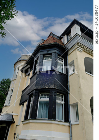 Low angle view of historic yellow building with prominent dark wood bay window Low angle view of historic yellow building with prominent dark wood bay window 141088477
