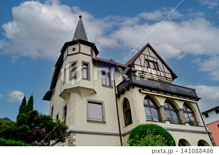 Elegant historic villa with a corner tower balcony and arched windows against a bright blue sky Elegant historic villa with a corner tower balcony and arched windows against a bright blue sky 141088486