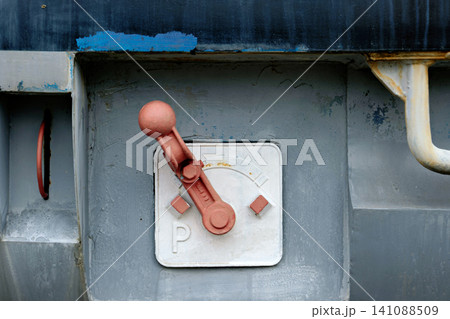 Vintage red mechanical parking brake lever on industrial railway wagon panel 141088509