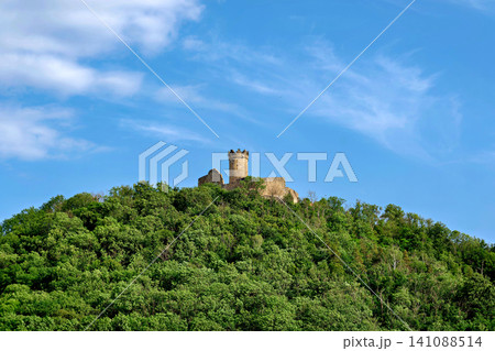 Ancient stone castle tower ruin on top of a lush green forested hill Ancient stone castle tower ruin on top of a lush green forested hill 141088514