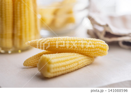 Fresh Baby Corn Cobs On Kitchen Counter With Jarred Preserved Vegetables For Cooking 141088596