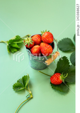 Ripe garden strawberries with leaves on pastel green Ripe garden strawberries with leaves on pastel green 141088627