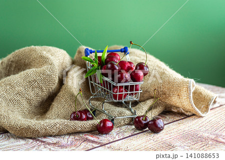 Fresh ripe cherries in miniature shopping cart with mint leaves Fresh ripe cherries in miniature shopping cart with mint leaves 141088653