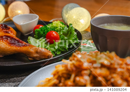 手前はボケたパスタ、奥にフォーカスされたローストチキンとサラダが並ぶ食卓 手前はボケたパスタ、奥にフォーカスされたローストチキンとサラダが並ぶ食卓 141089204