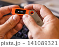hardware Bitcoin wallet in a hands with message RISK on screen 141089321