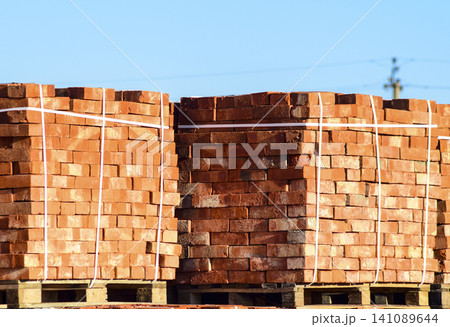 Red bricks stacked into cubes. Warehouse bricks. Storage brickworks products Red bricks stacked into cubes. Warehouse bricks. Storage brickworks products 141089644