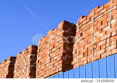 Red bricks stacked into cubes. Warehouse bricks. Storage brickworks products Red bricks stacked into cubes. Warehouse bricks. Storage brickworks products 141089830