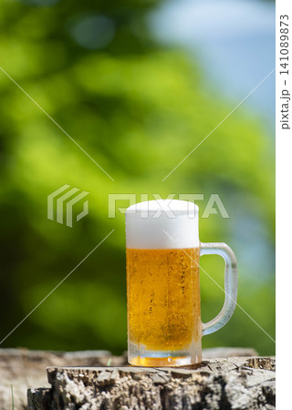 夏の野外でビールを楽しむ、冷えたグラスと白い泡が涼しさを演出する瞬間 夏の野外でビールを楽しむ、冷えたグラスと白い泡が涼しさを演出する瞬間 141089873