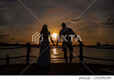 Romantic couple silhouette at golden sunset by sea Romantic couple silhouette at golden sunset by sea 141090264