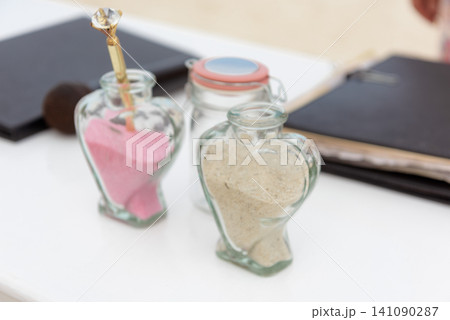 Heart shaped glass bottles filled with pink and white sand on table Heart shaped glass bottles filled with pink and white sand on table 141090287