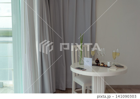 White table with champagne glasses and desserts near grey curtains White table with champagne glasses and desserts near grey curtains 141090303