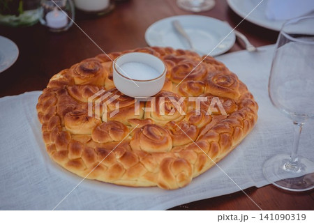 Traditional round bread with salt bowl on wooden table 141090319