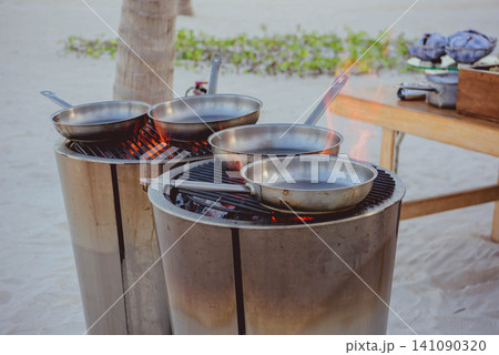 Outdoor cooking station with pans over charcoal grills Outdoor cooking station with pans over charcoal grills 141090320