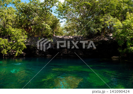 Cenote with turquoise water and rocky cliff 141090424