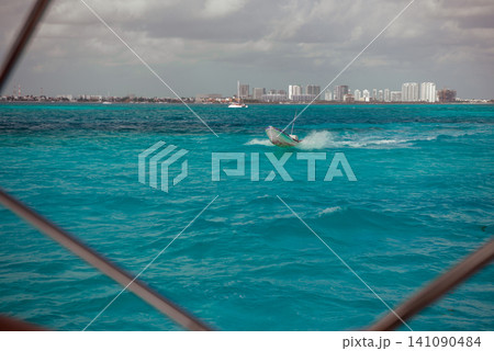 Small boat speeding across turquoise ocean water Small boat speeding across turquoise ocean water 141090484