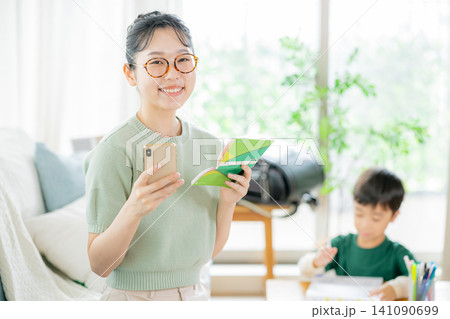 リビングで通帳とスマホを見る母親 141090699