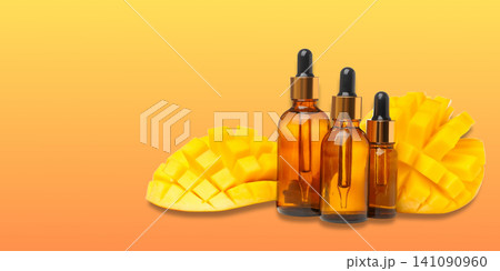 Bottles filled with mango oil rest beside sliced mango fruit Bottles filled with mango oil rest beside sliced mango fruit 141090960