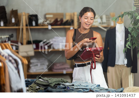 While shopping, girl scans barcode on label of handbag While shopping, girl scans barcode on label of handbag 141091437