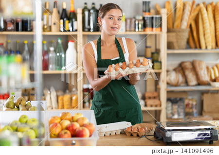 Young woman seller offering eggs in grocery store Young woman seller offering eggs in grocery store 141091496