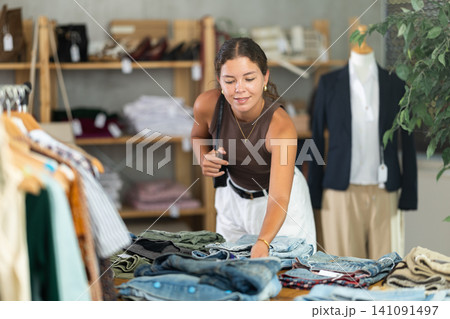 Brunette chooses jeans in store Brunette chooses jeans in store 141091497
