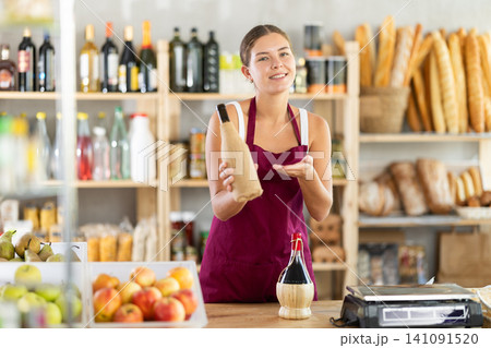 Female salesperson offers to buy bottle of wine in liquor department of grocery supermarket 141091520
