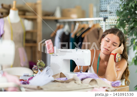 woman dressmaker sits tired at the table woman dressmaker sits tired at the table 141091530