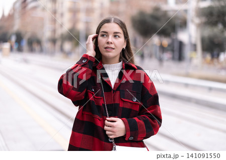 woman stands at a public transport stop 141091550