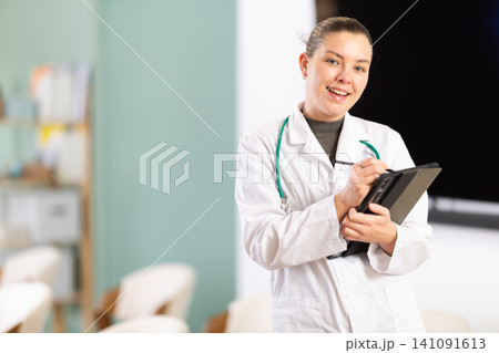 Doctor girl office employee with tablet greets and invite visitors 141091613