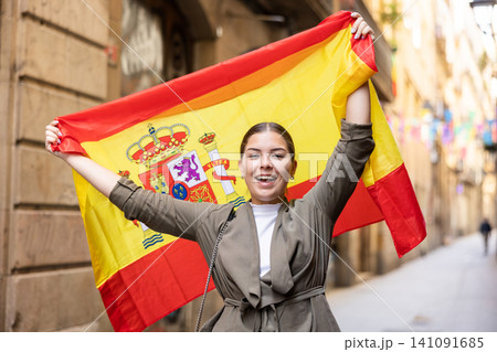 Happy female tourist walking old streets with flag of spain 141091685