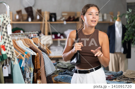 Young woman comes to boutique and looks at clothes 141091720