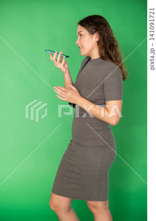 Young woman recording voice message in front of green screen Young woman recording voice message in front of green screen 141091721