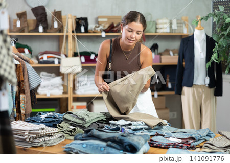 Woman standing near shelves with pants in a store Woman standing near shelves with pants in a store 141091776