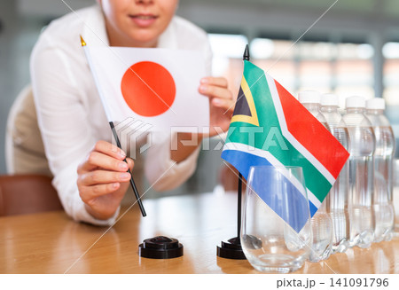 Blurry girl set midget flags of South Africa and Japan before international negotiations 141091796