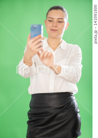 Young woman on green screen background take photo by phone camera Young woman on green screen background take photo by phone camera 141091800