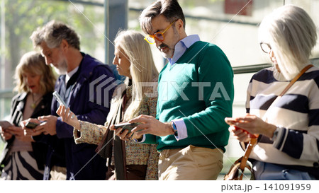 People absorbed using smartphones in public People absorbed using smartphones in public 141091959