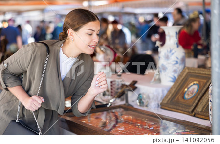 Curious female tourist looking to buy some pretty jewelry at flea market 141092056