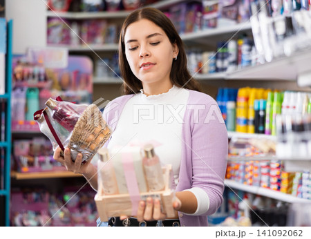 Smiling woman chooses a gift set for someone in cosmetics store Smiling woman chooses a gift set for someone in cosmetics store 141092062