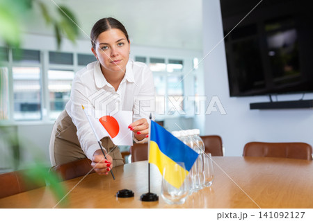 Young lady sets miniatures flags of Ukraine and Japan for international negotiations Young lady sets miniatures flags of Ukraine and Japan for international negotiations 141092127