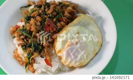 stir fried pork with holy basil on top with fried egg on cooked rice stir fried pork with holy basil on top with fried egg on cooked rice 141092171