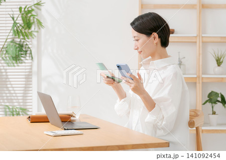 通帳を見て微笑む女性 141092454
