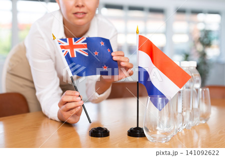 Unrecognizable girl sets midget flags of Netherlands and Australia before international negotiations Unrecognizable girl sets midget flags of Netherlands and Australia before international negotiations 141092622