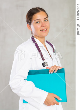 Happy female doctor standing with file in hands 141092843