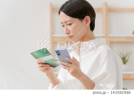 通帳を見て落ち込む女性 141092986
