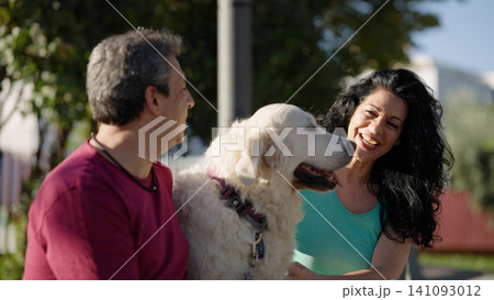 Couple interacting with golden retriever dog in park Couple interacting with golden retriever dog in park 141093012