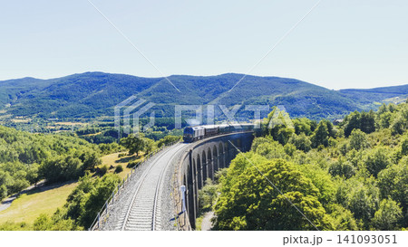 Vintage train traveling over railway viaduct in mountains 141093051