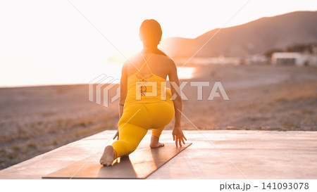 Woman doing yoga pose on beach at sunset 141093078