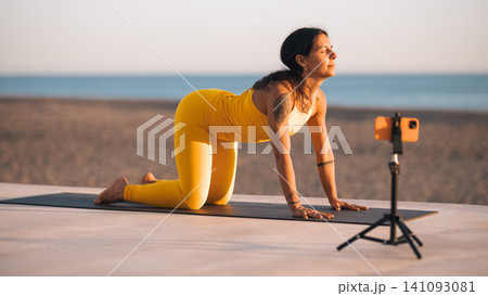 Woman filming outdoor yoga workout for social media Woman filming outdoor yoga workout for social media 141093081
